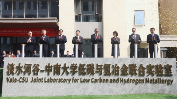 A group of people standing in front of a sign

Description automatically generated